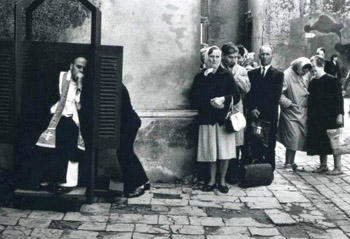 Black and white photograph of a long line for conefession outside a Church