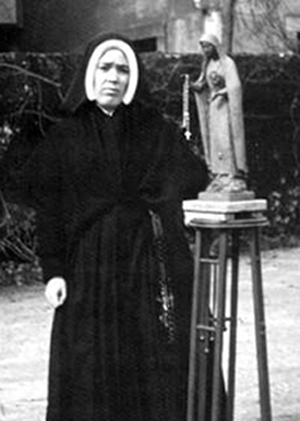 Sister Lucia standing beside a statue of Our Lady