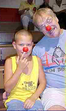 A casually dressed father and son wearing clown noses