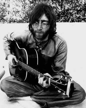 John Lennon sitting Indian style with his guitar