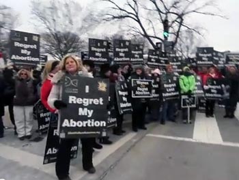 Women holding signs saying 'I regret my abortion'
