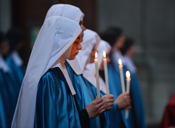 Young postulant nuns wearing habits and holding candles