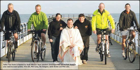 Fr Paul Farrer on a pier with bicyclists