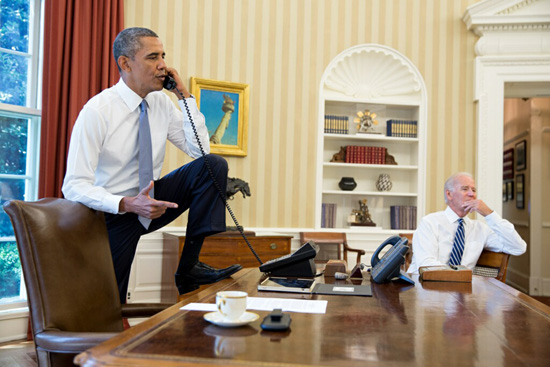 Obama with one foot up on the desk of the Oval Office