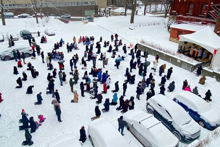 Montreal Catholics kneeling outside Cathedral during outdoor Mass in winter