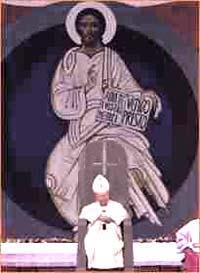 John Paul II sitting on a throne with an inverted cross in front of an Image of Our Lord